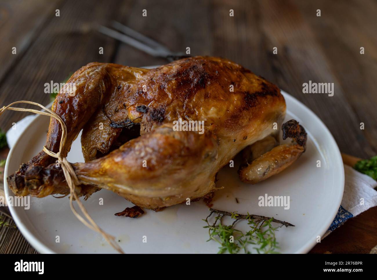 Oven roasted whole chicken on a plate isolated on wooden table Stock Photo