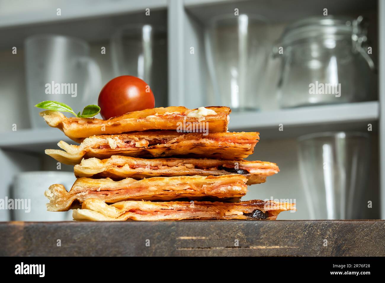 Homemade pizza waffle with tomato sauce, pepperoni, olives and parmesan cheese on a cutting board on the kitchen table Stock Photo