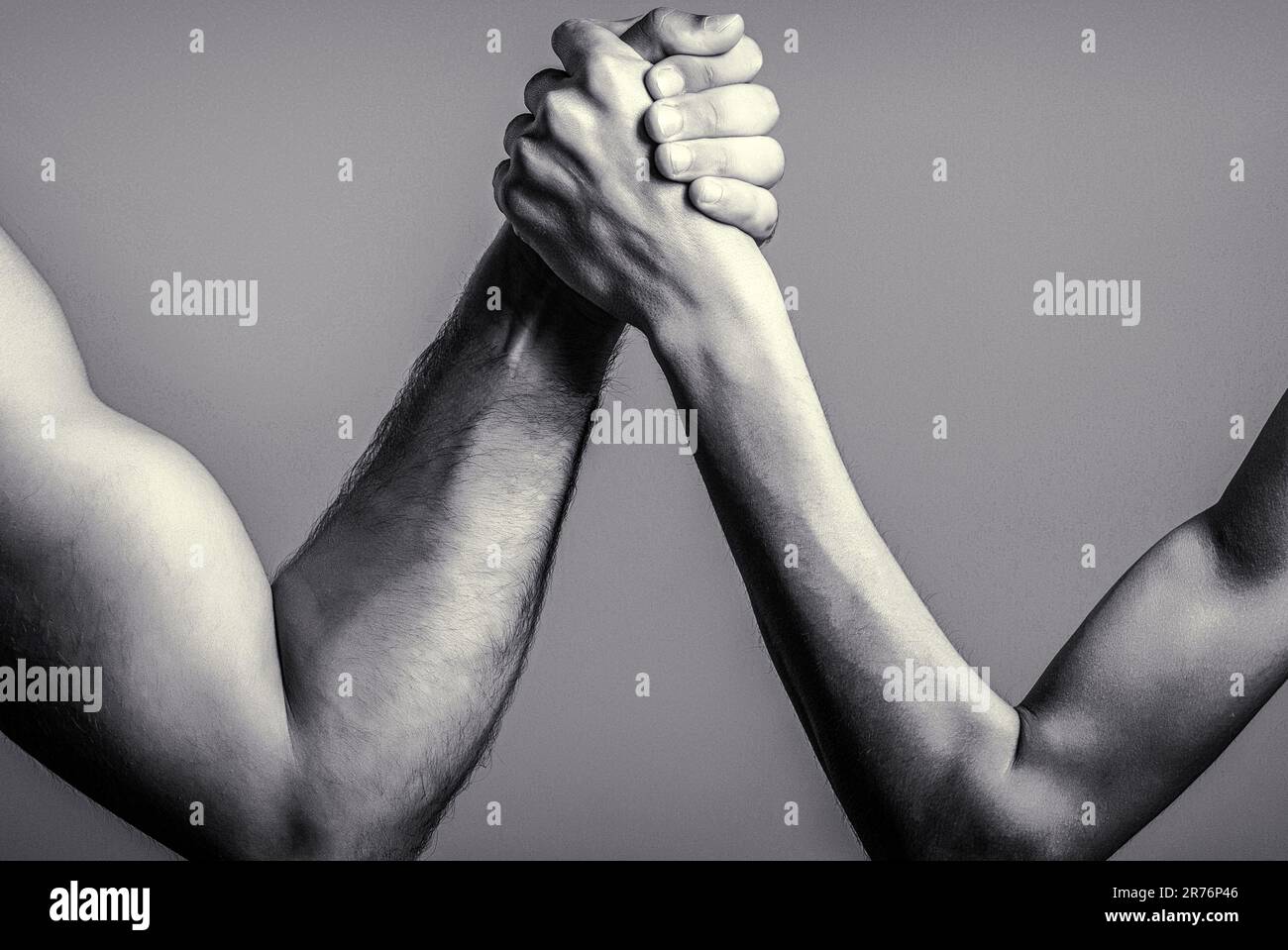 Two man's hands clasped arm wrestling, strong and weak, unequal match