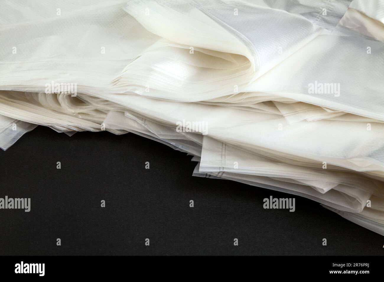 Pile of clear new plastic bags with handles for shopping and carrying things. Many disposable transparent polyethylene bags - Stock Image