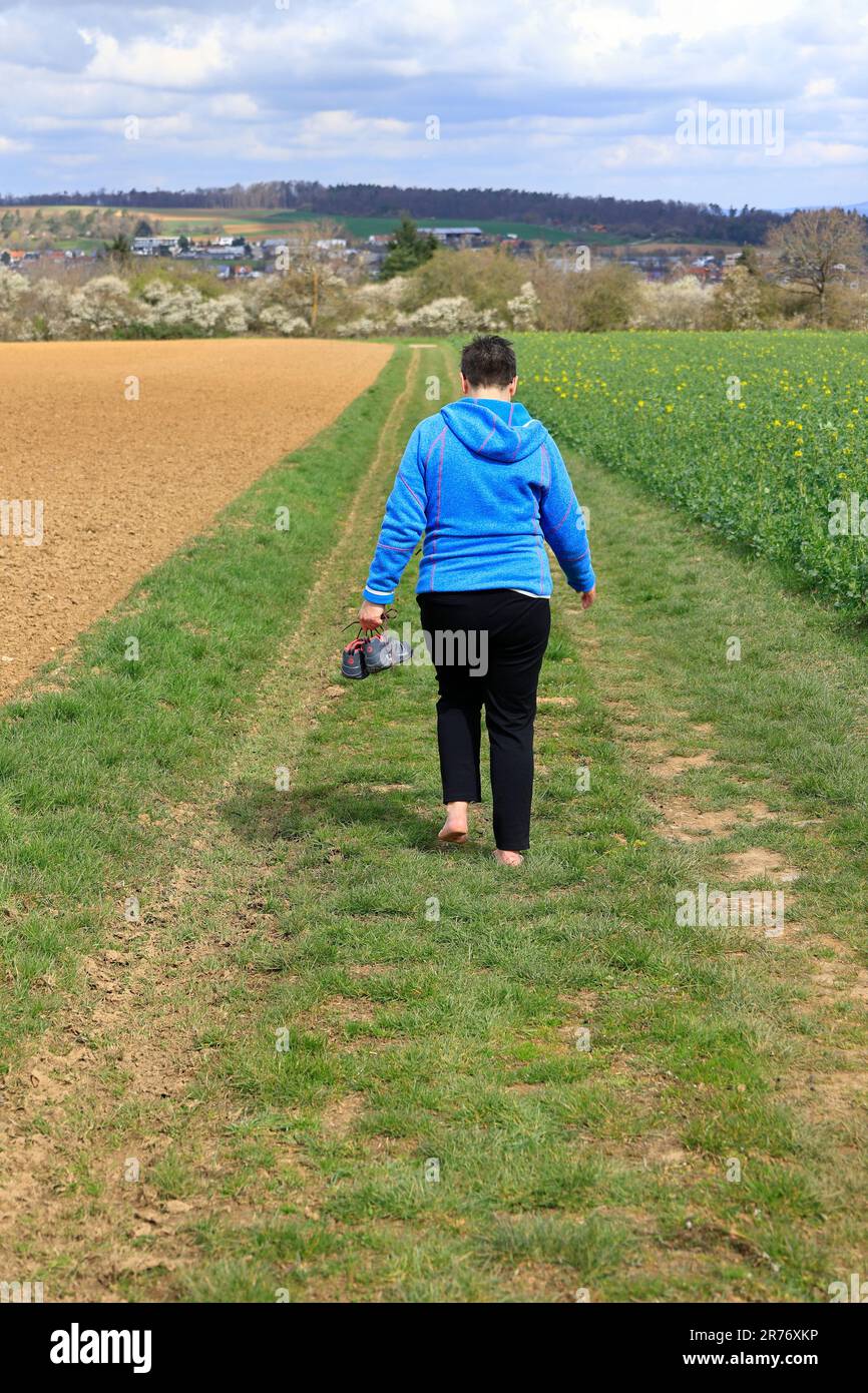 Woman walks without shoes on a dirt road Stock Photo