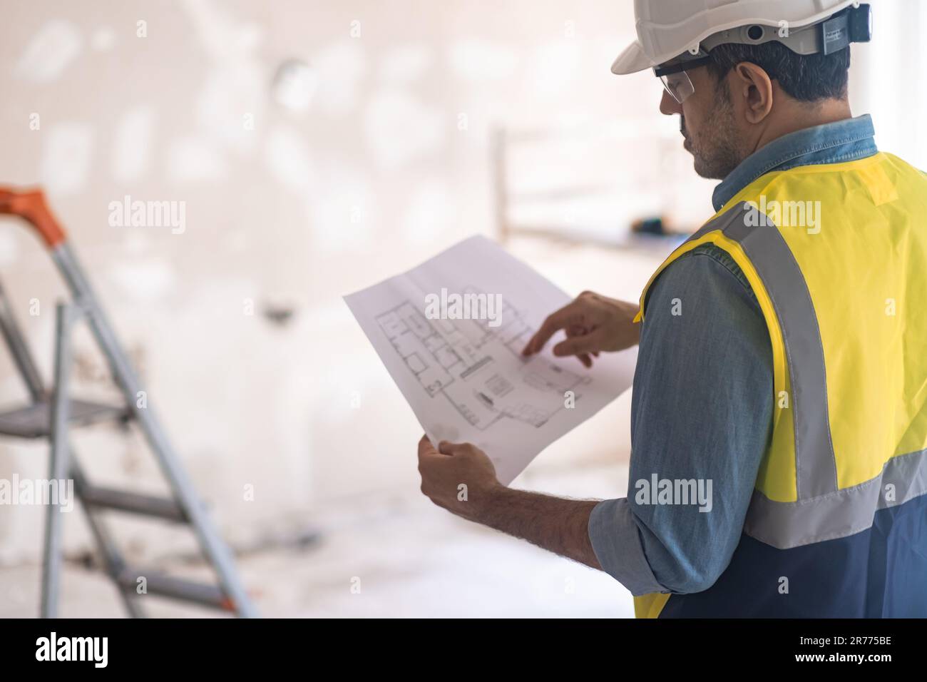 Engineer in professional uniform holds apartment project plan checking ...