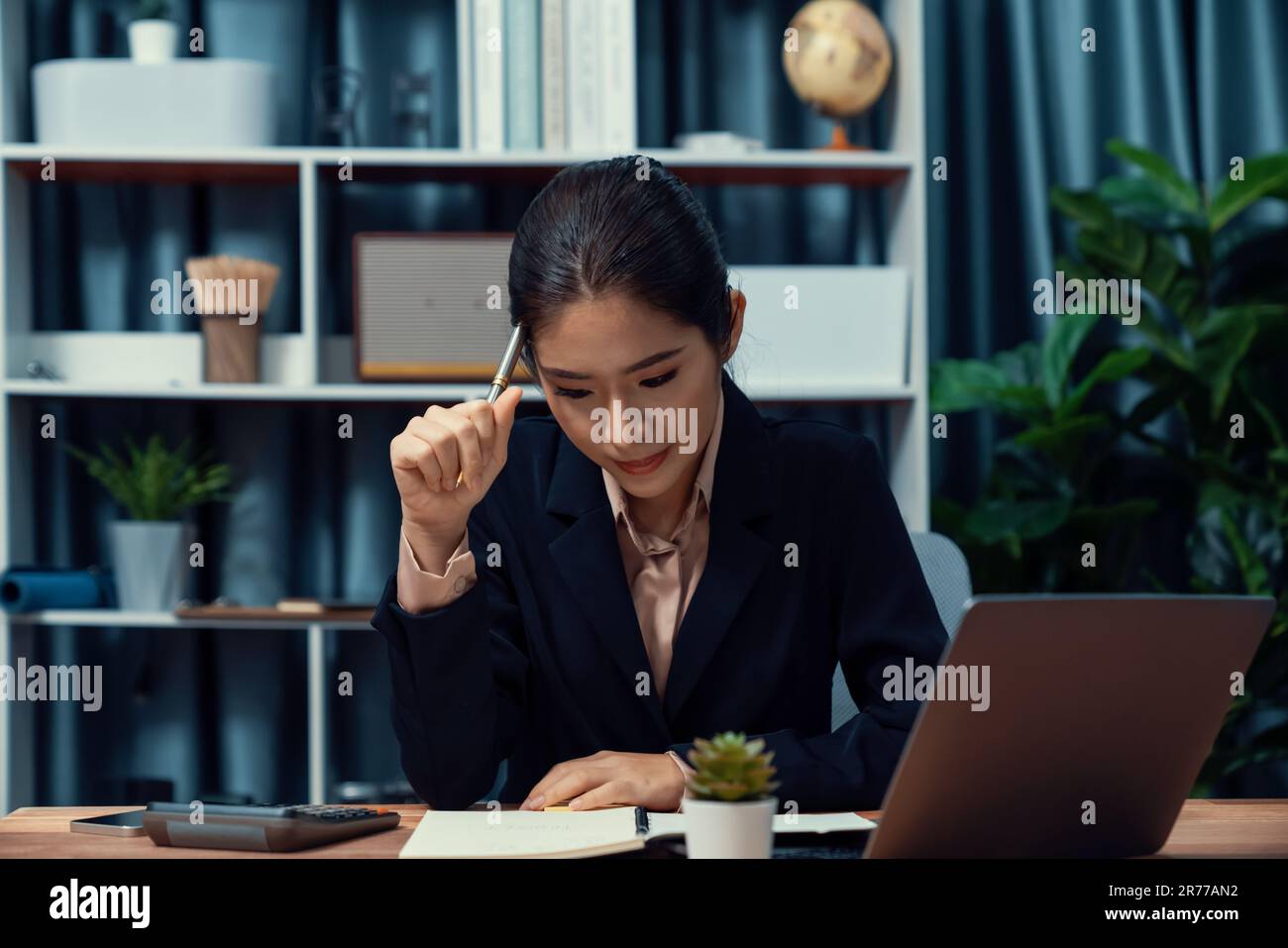 Young asian businesswoman is diligently working and taking notes in her ...