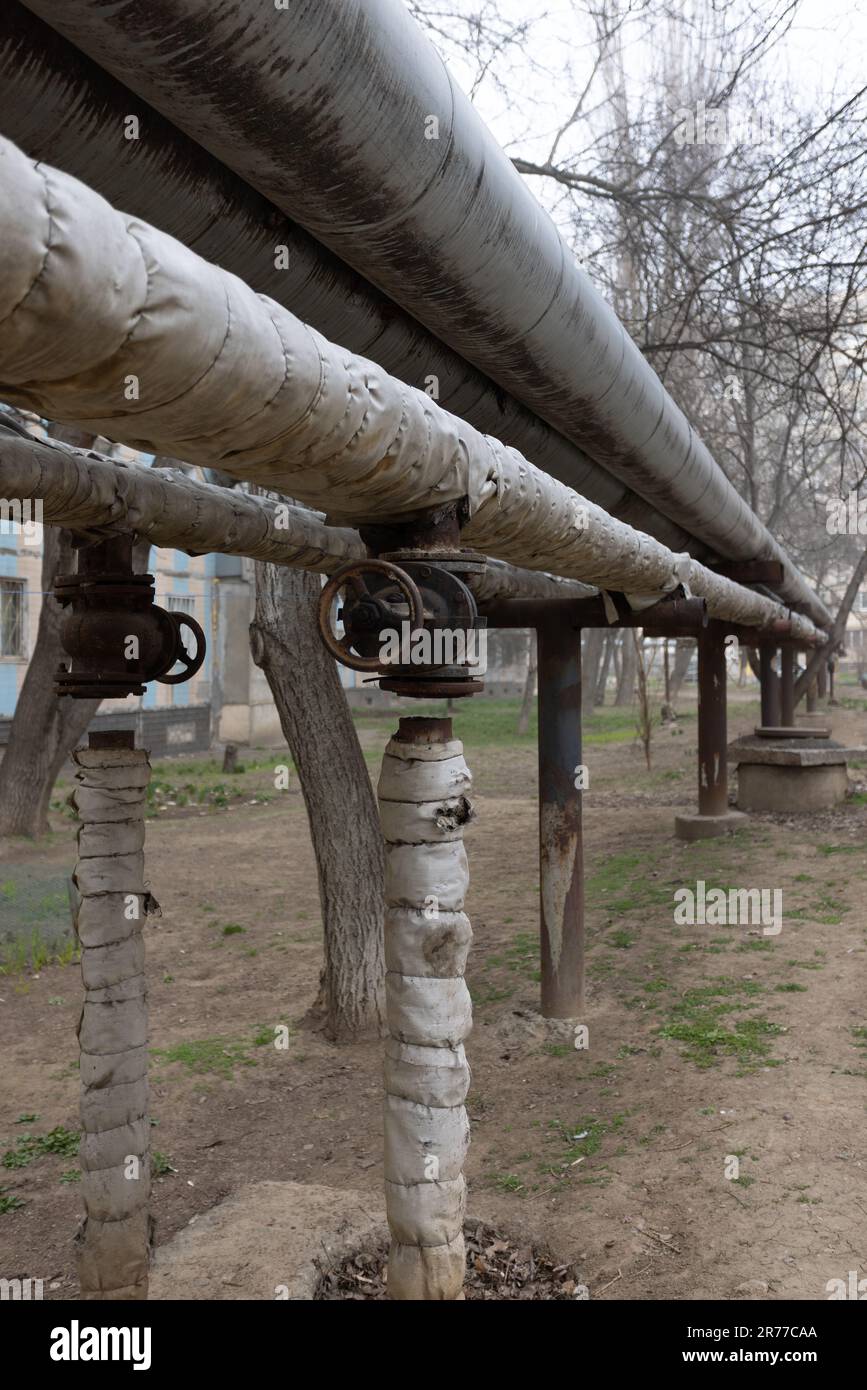 Old air heating main with valve turned off. Concept of desolation, poverty, bankruptcy and devastation. Heating pipe is laid in open air above ground, Stock Photo