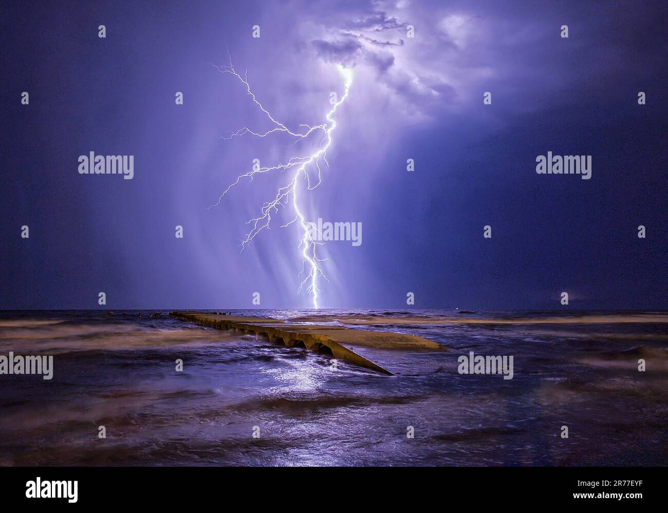 Dramatic image of a pier illuminated by a powerful bolt of lightning ...