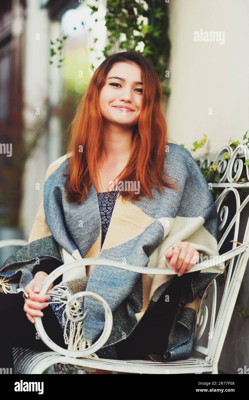Young fashion 20 year old girl sitting on the bench, wearing warm plaid jacket Stock Photo Alamy