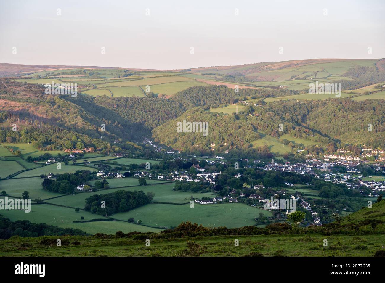 Morning sun shines on the hills of Exmoor above Porlock village in West Somerset. Stock Photo