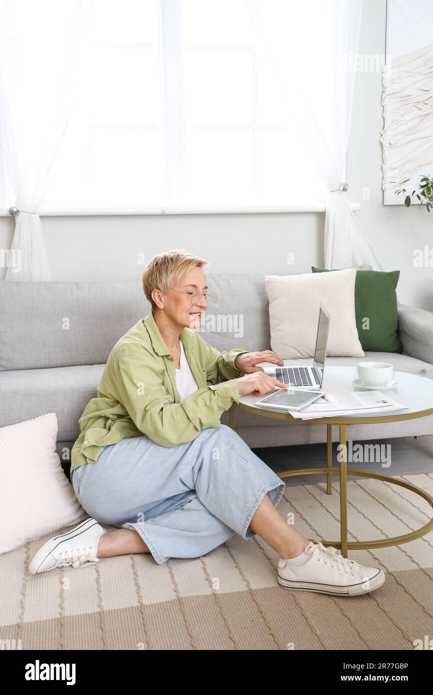 Mature female programmer working with tablet computer and laptop at home Stock Photo