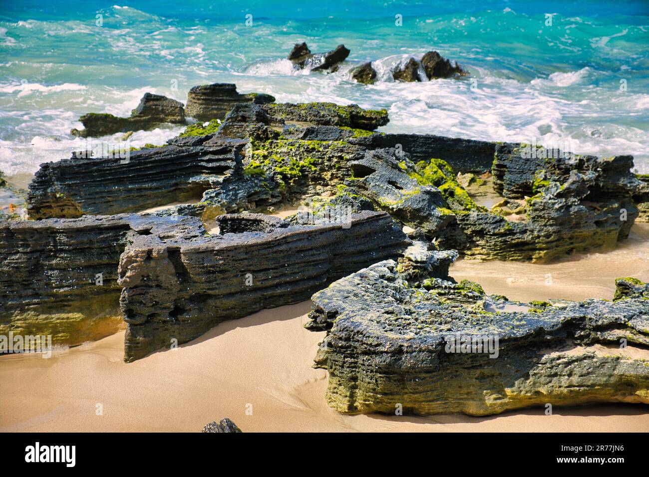 Algae-covered pancake rocks on a beach with wild waves, Esperance, Western Australia Stock Photo