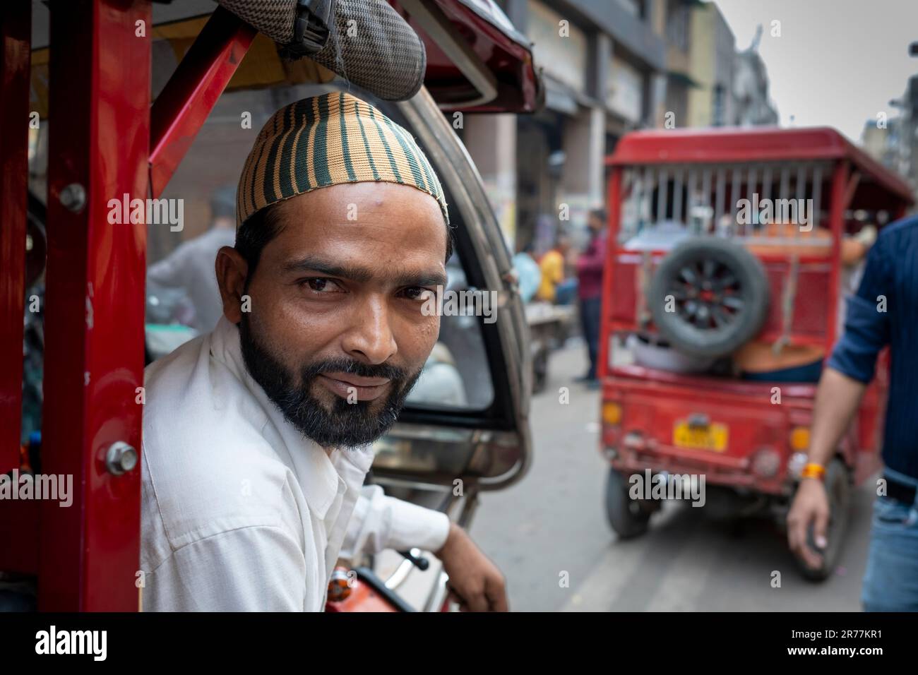 Pedal rickshaw cab driver takes break in busy market, Old Delhi section