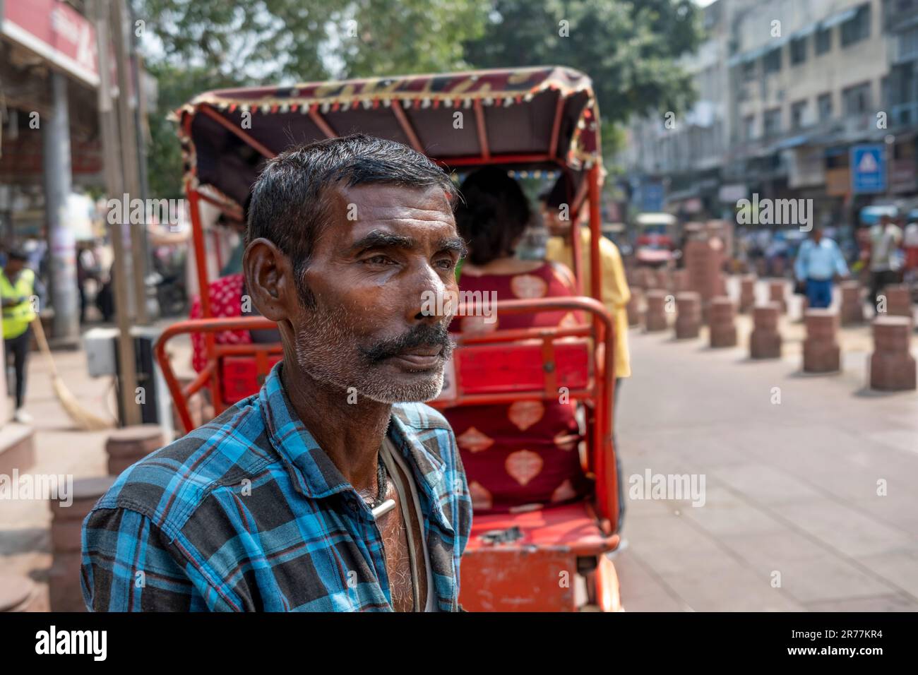 Pedal rickshaw cab driver takes break in busy market, Old Delhi section