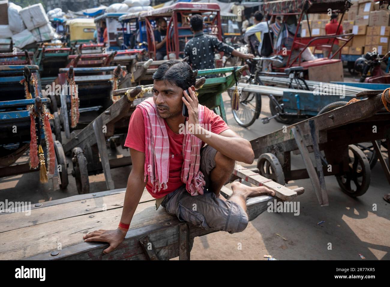 Pedal rickshaw cab driver takes break in busy market, Old Delhi section