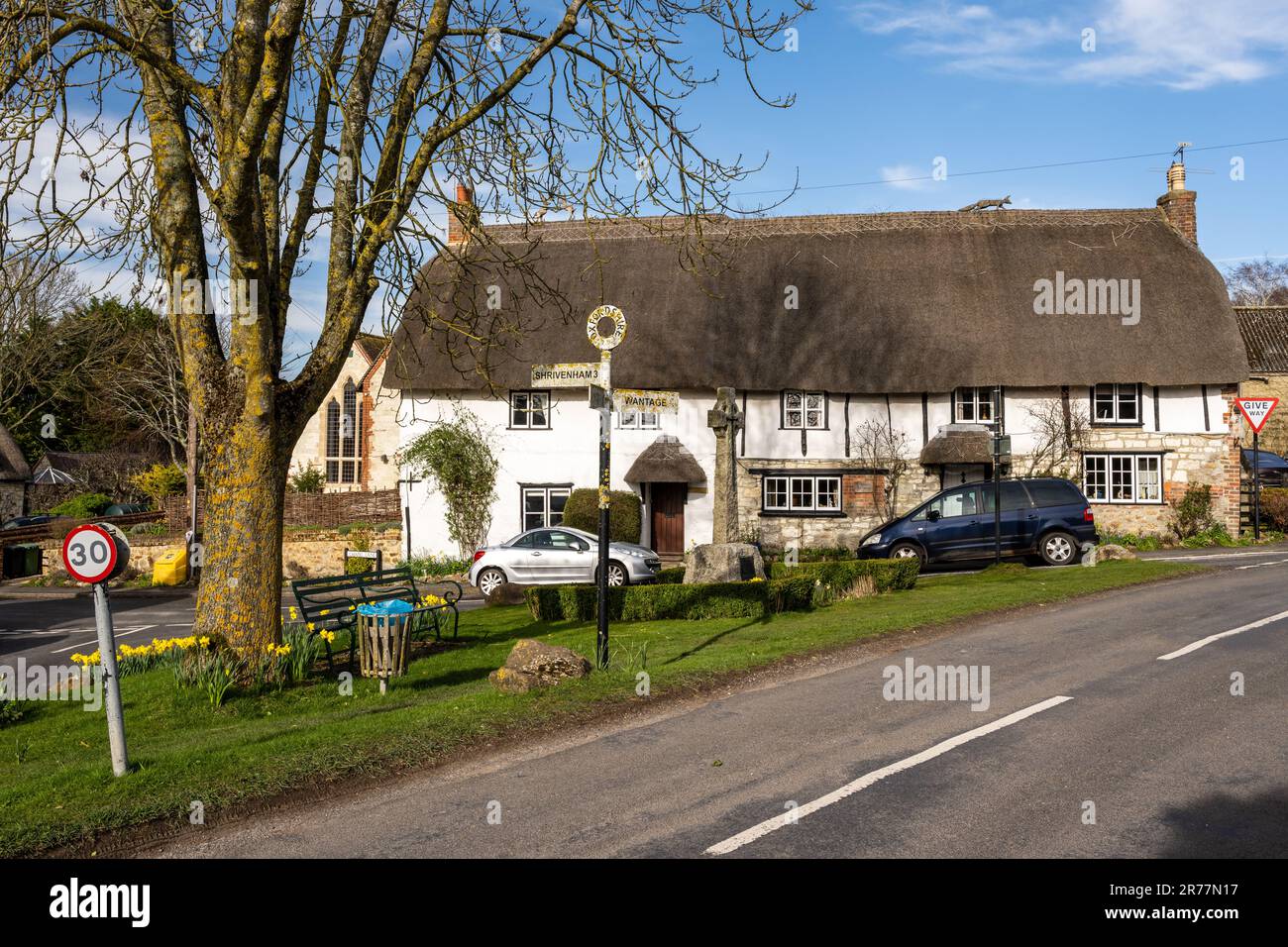 Traditional thatched cottages stand alongside the village green in Ashbury in Oxfordshire's Vale of White Horse. Stock Photo