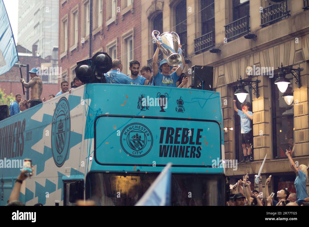 Manchester City football team open top bus parade during rain. Text Treble Winners June 2023 . Cup held up. Stock Photo