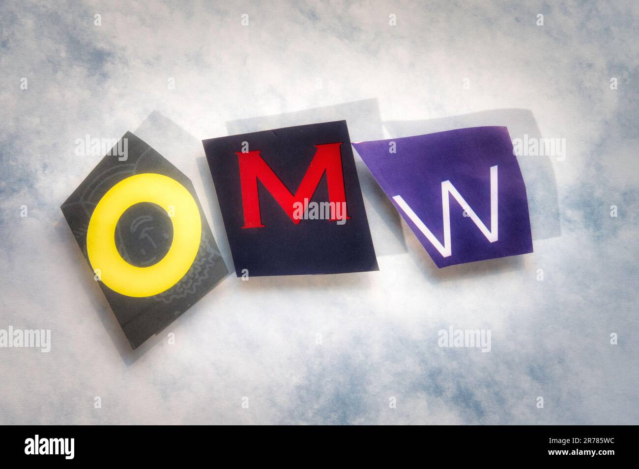 The acronym 'OMW' (On my way!) using cut-out paper letters in the ransom note effect typography, USA Stock Photo