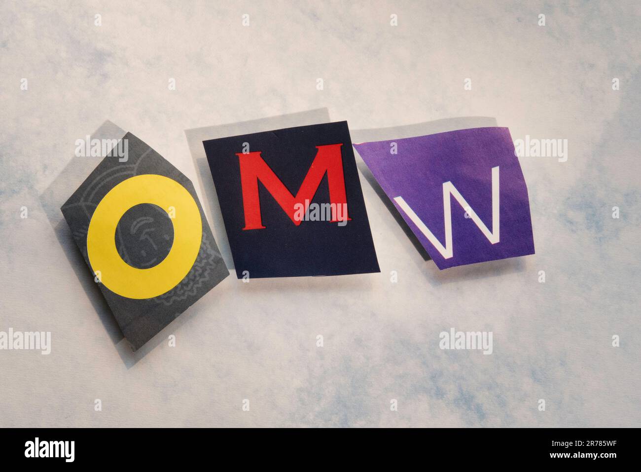 The acronym 'OMW' (On my way!) using cut-out paper letters in the ransom note effect typography, USA Stock Photo