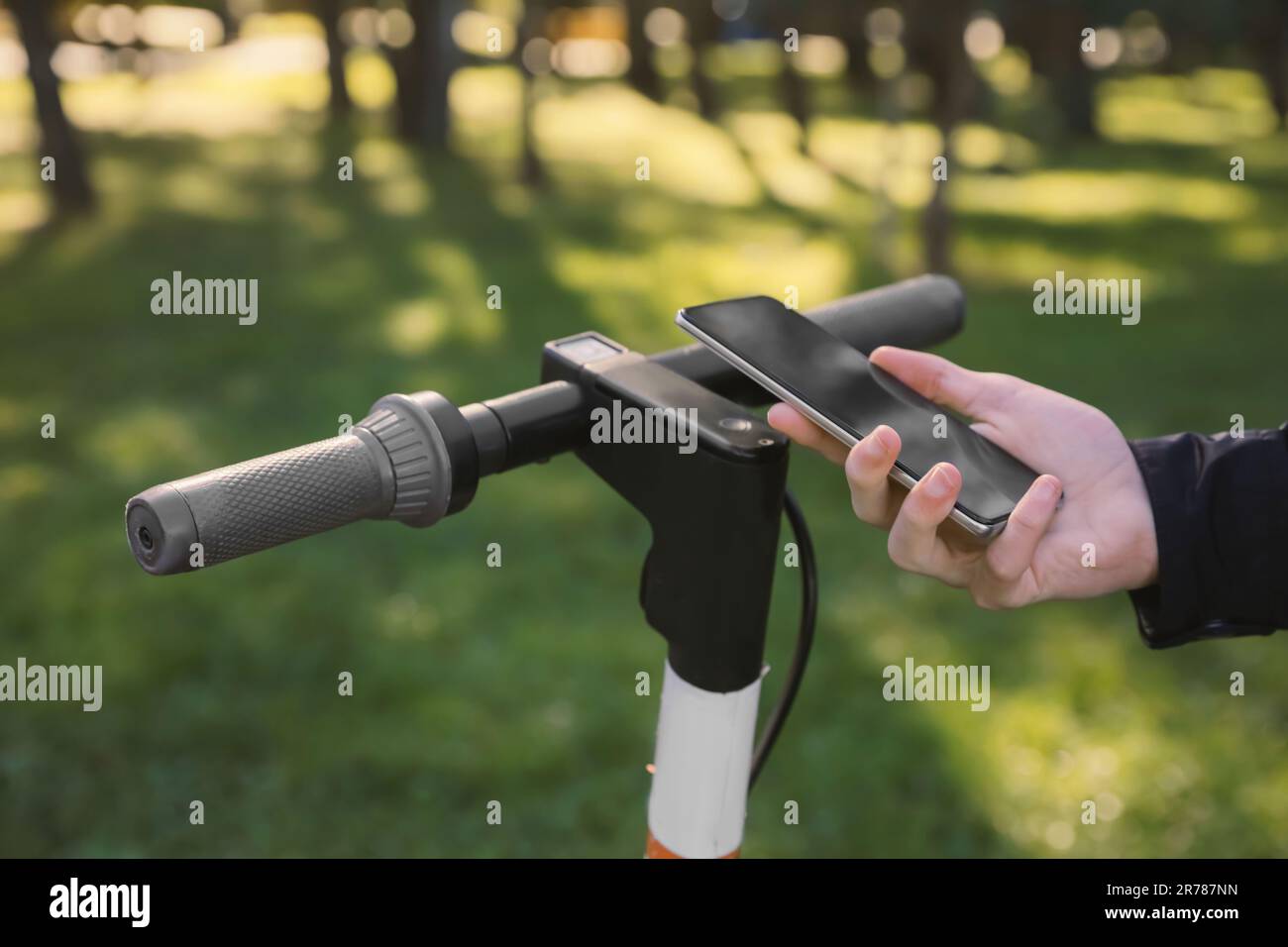 Man using smartphone to pay and unblock rental electric scooter outdoors, closeup Stock Photo
