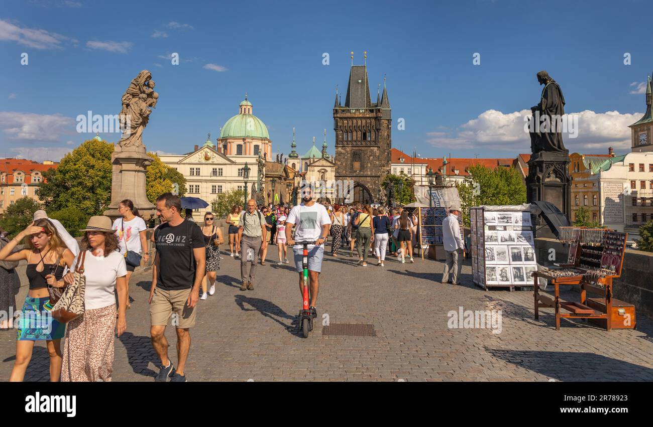 PRAGUE, CZECH REPUBLIC - Tourists crossing Charles Bridge, man on scooter. Old Town Bridge Tower at rear. Stock Photo