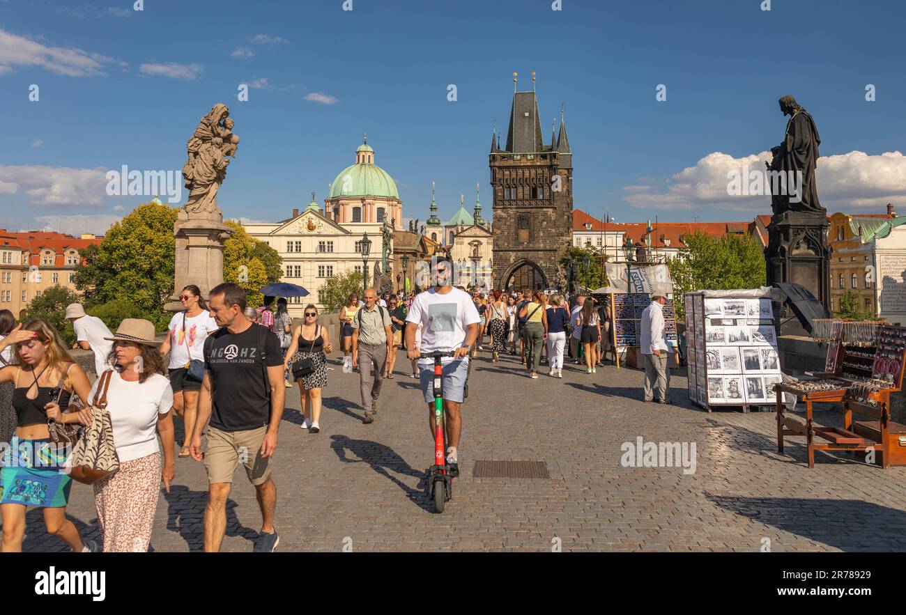 PRAGUE, CZECH REPUBLIC - Tourists crossing Charles Bridge, man on scooter. Old Town Bridge Tower at rear. Stock Photo