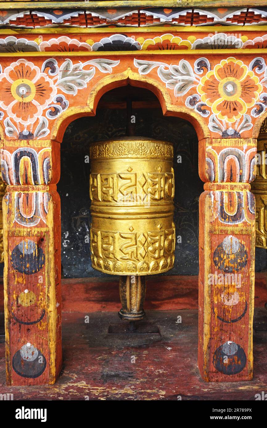 Colorful gilded prayer wheel set in a traditional arched painted wooden niche in Bhutan. Each spin of the wheel sends another prayer out in the world. Stock Photo
