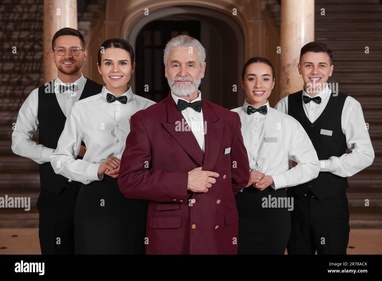 Group of young trainees with teacher in hotel. Professional butler Group of young trainees with teacher in hotel. Professional butler
