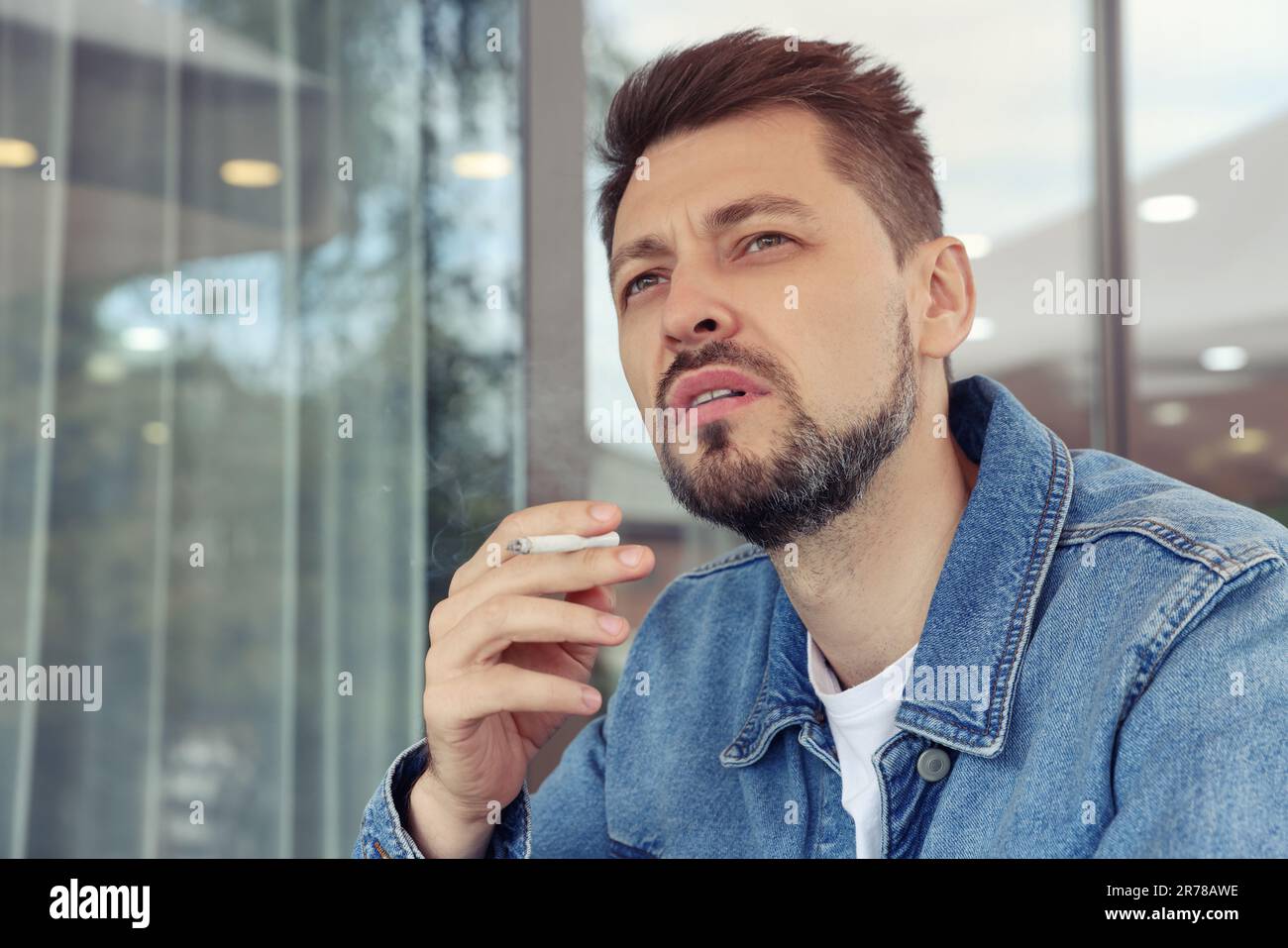 Handsome man smoking cigarette outdoors. Space for text Stock Photo