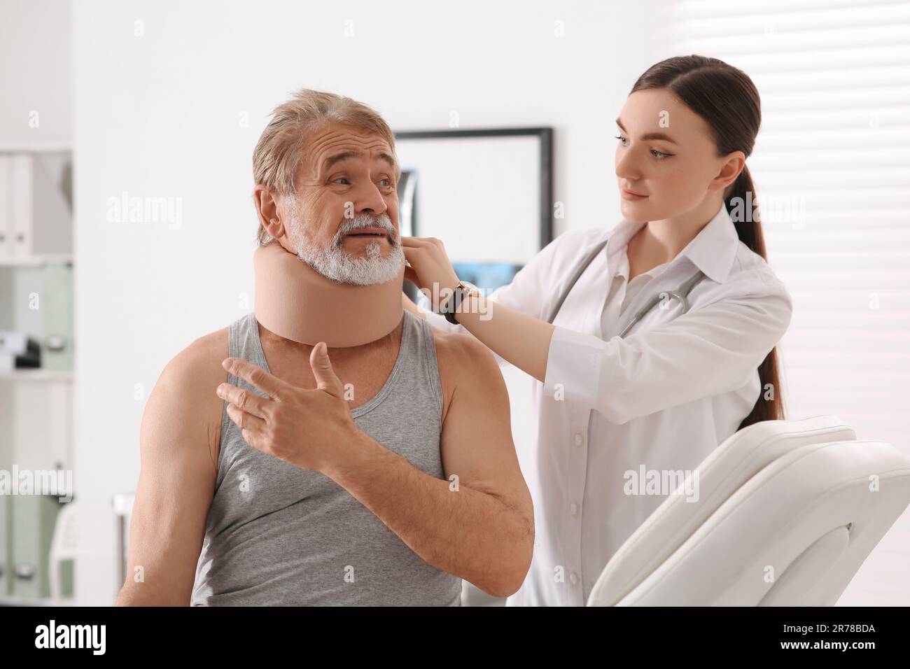 Orthopedist applying cervical collar onto patient's neck in clinic