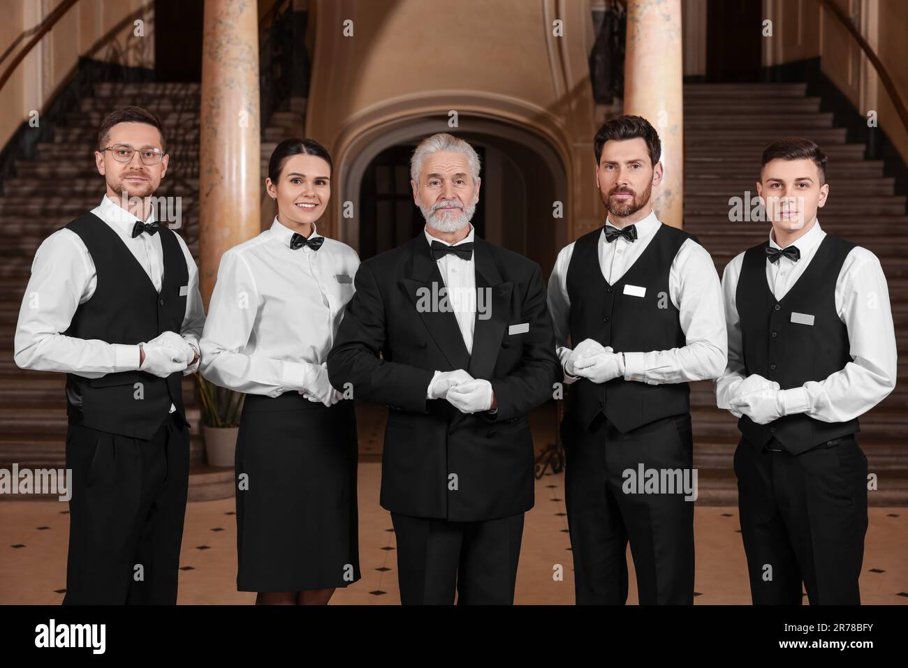 Group of young trainees with teacher in hotel. Professional butler Group of young trainees with teacher in hotel. Professional butler
