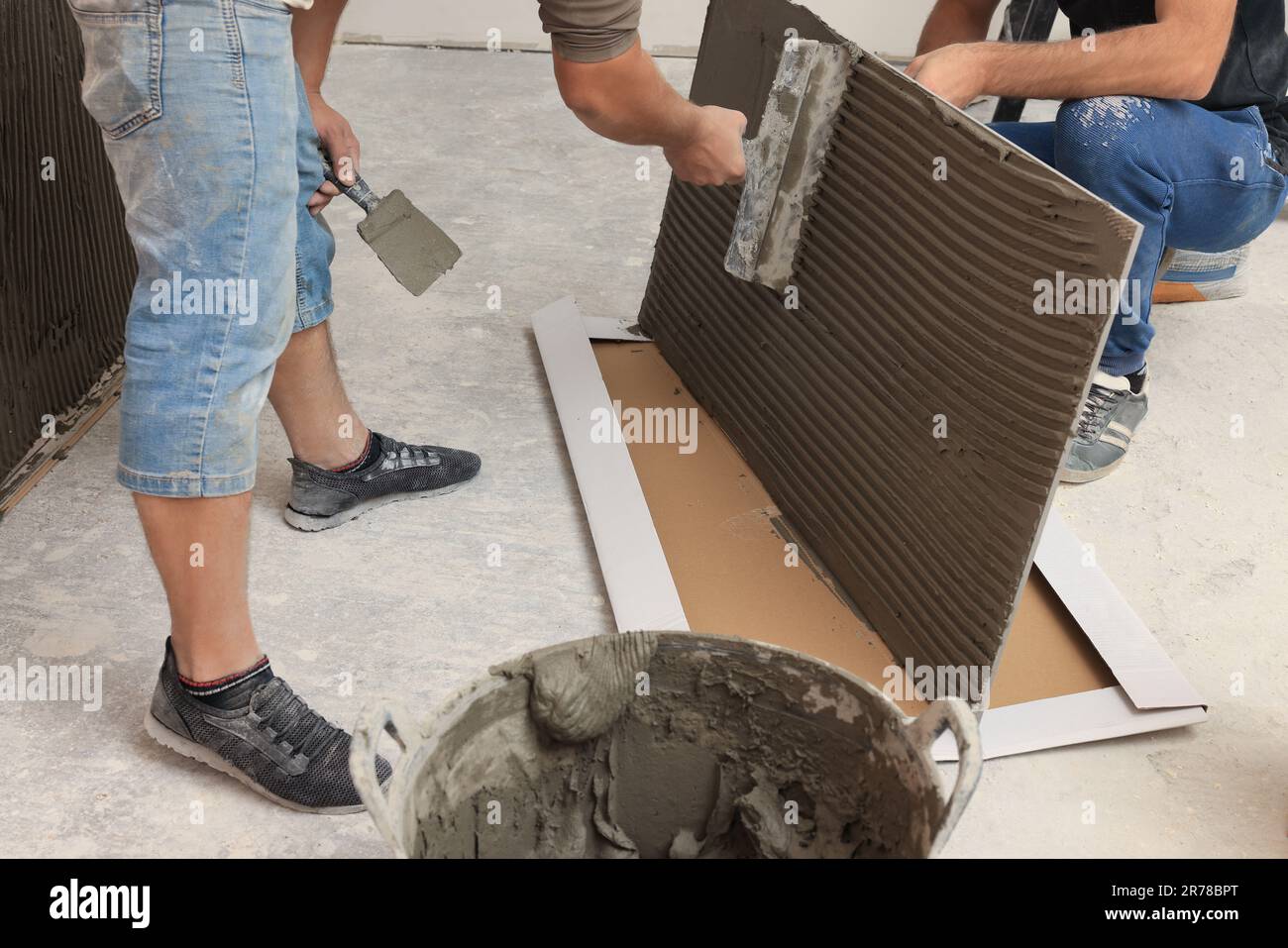 Worker spreading adhesive mix over tile with spatula, closeup Stock ...