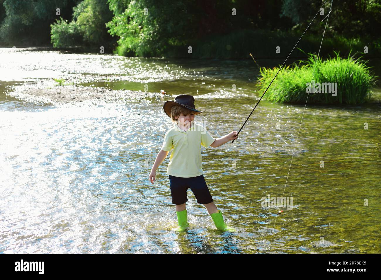 Child fishing. Kid learning how to fish holding a rod on a river. Little boy  fisherman with fishing rod. Young man fly fishing Stock Photo - Alamy