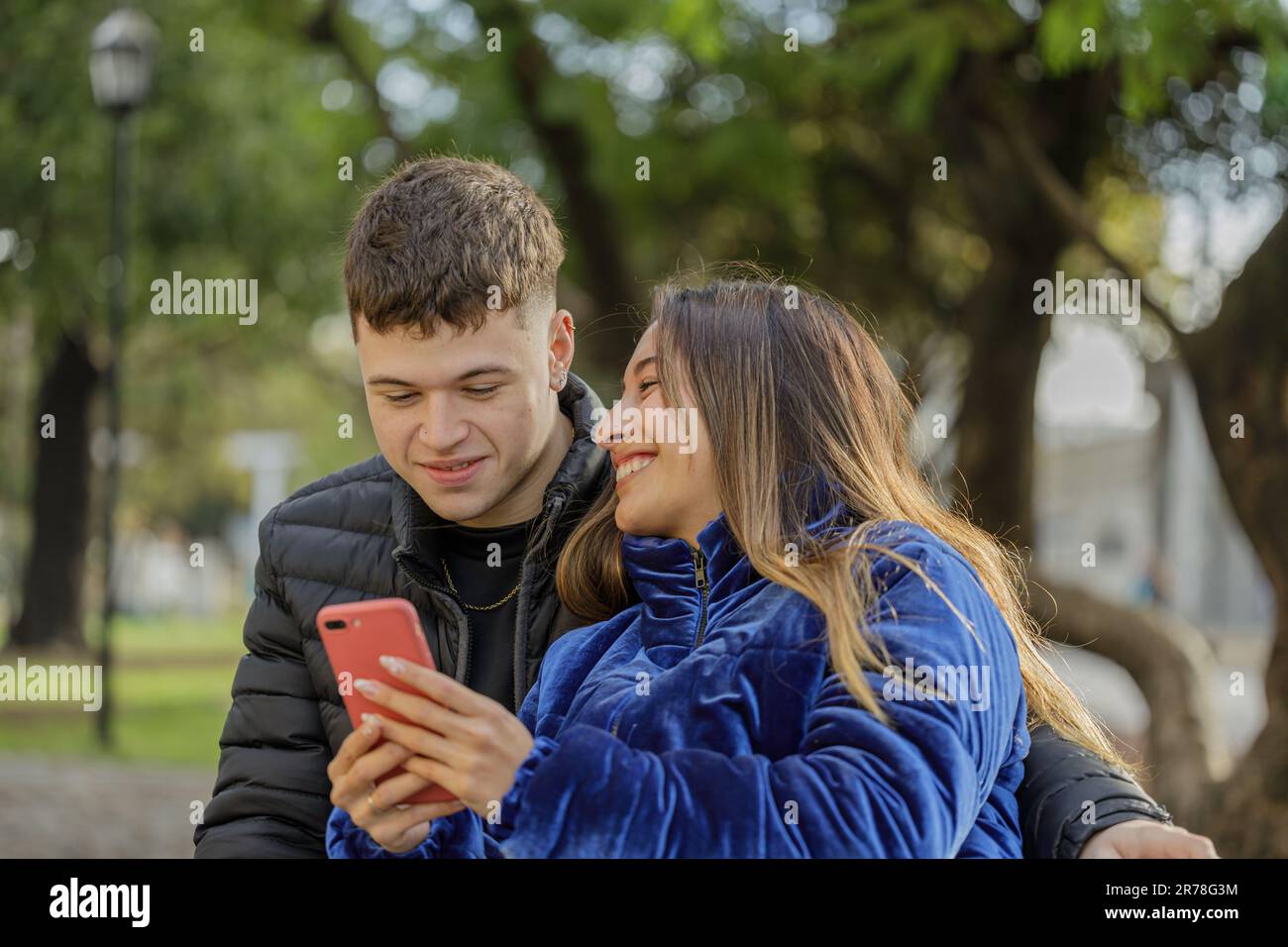 Young couple sitting on a bench in a public park. Stock Photo