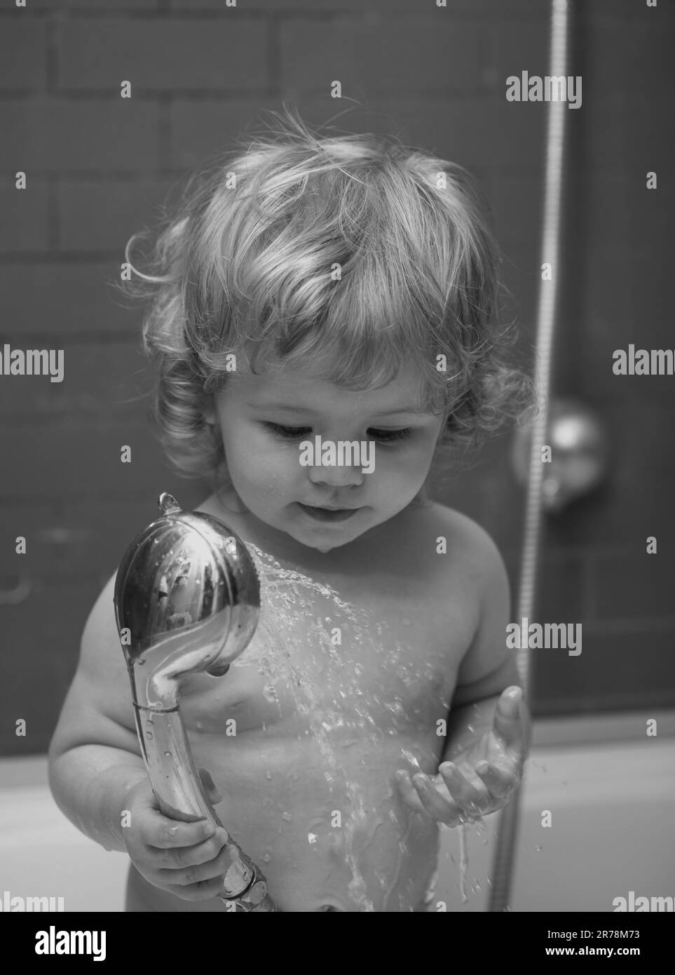 Funny baby kid bathed in foam and washing in bathtub at home Stock