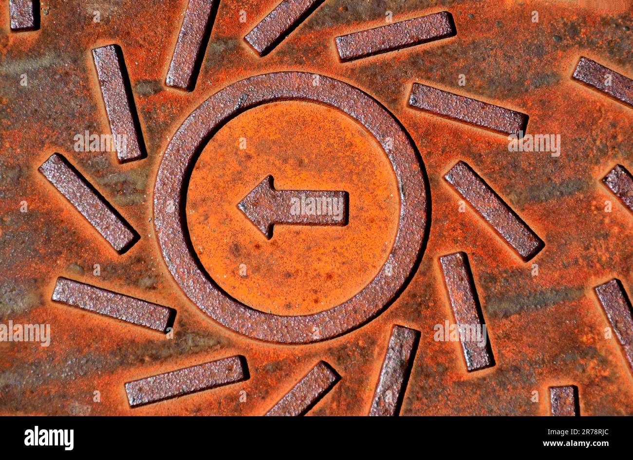 Rusty Red Brown Color Textured Cast Iron Manhole Cover Closeup Arrow rusty-red-brown-color-textured-cast-iron-manhole-cover-closeup-arrow