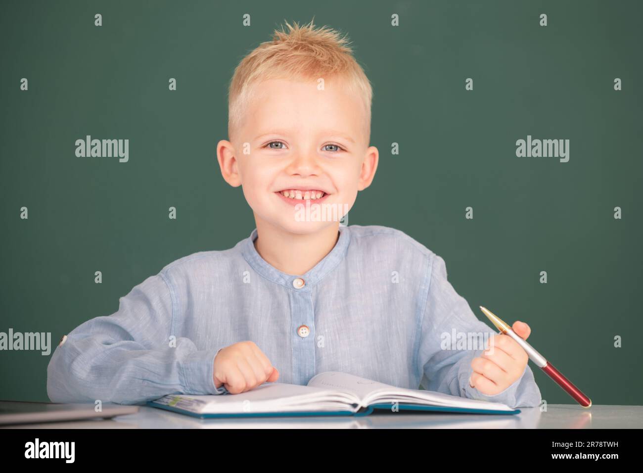 Kid writing in notebook in class. Little schoolboy study in a classroom ...
