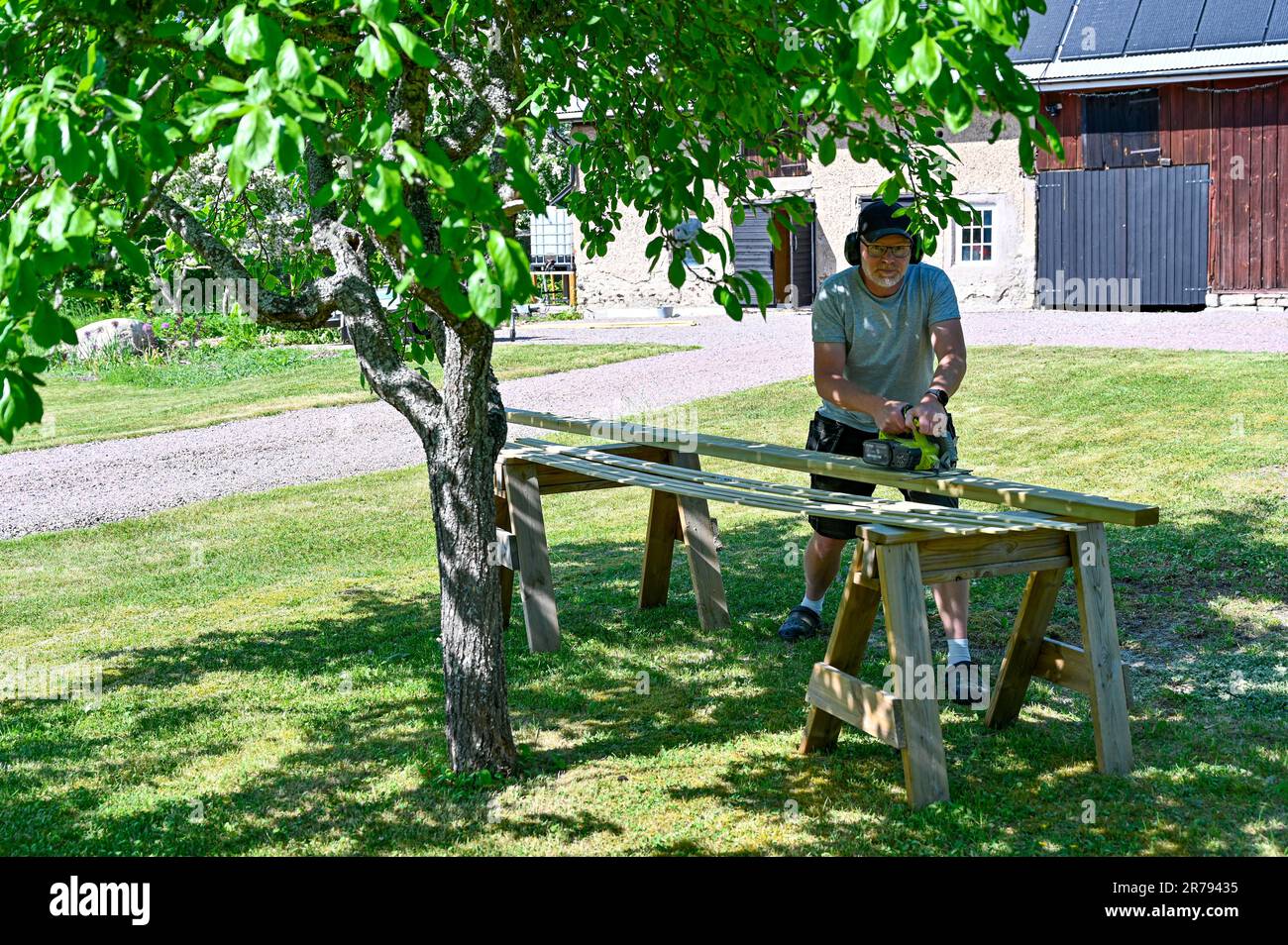 man standing in garden cutting planks with circle saw Stock Photo - Alamy