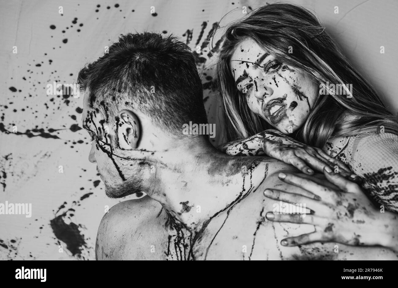 Halloween zombie couple of muscular man and bloody young woman with wounds and red blood. A bloody couple, a vampire girl bites a muscular man by the Stock Photo