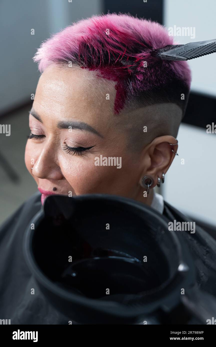 Close-up of the process. The hairdresser dyes the hair of an Asian woman in  pink. Short extreme haircut Stock Photo - Alamy, image size:864x1390