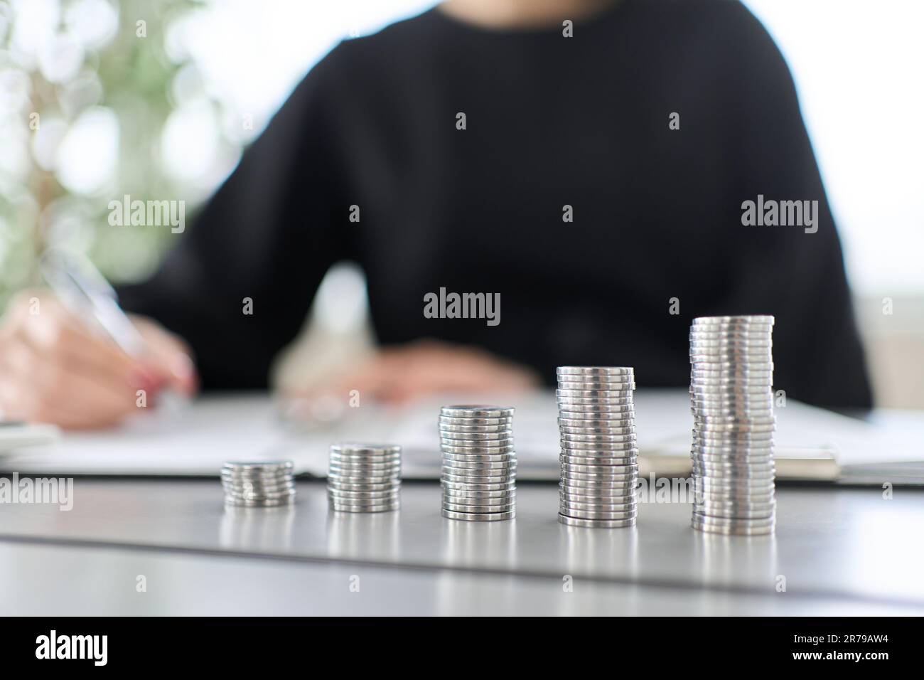 A woman studying investment and a coin stack Stock Photo Alamy