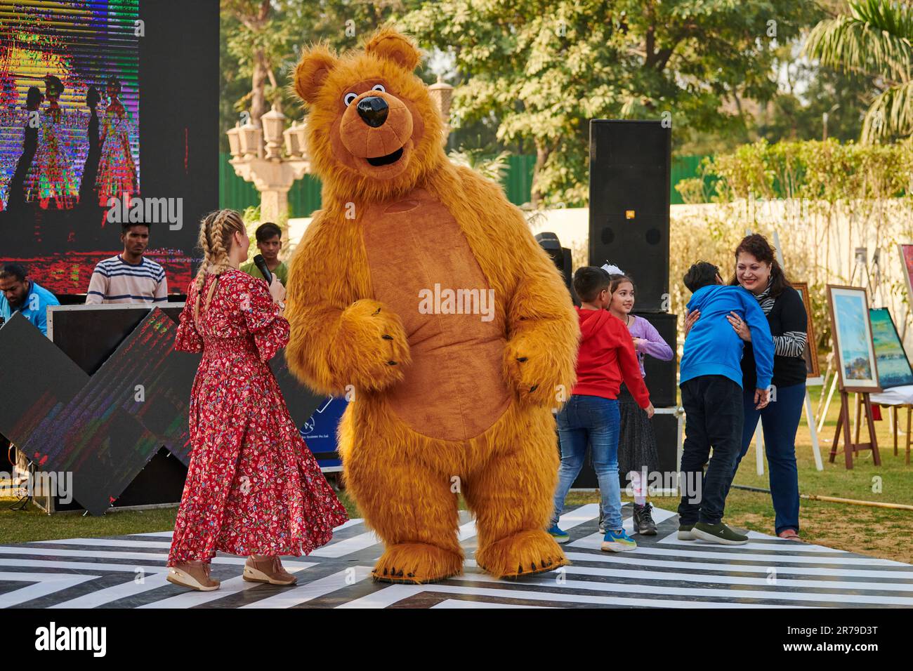 New Delhi, India - 10.12.2022 - Children outdoor party dancing with brown teddy bear, funny children games with big toy teddy bear, happy childhood co Stock Photo