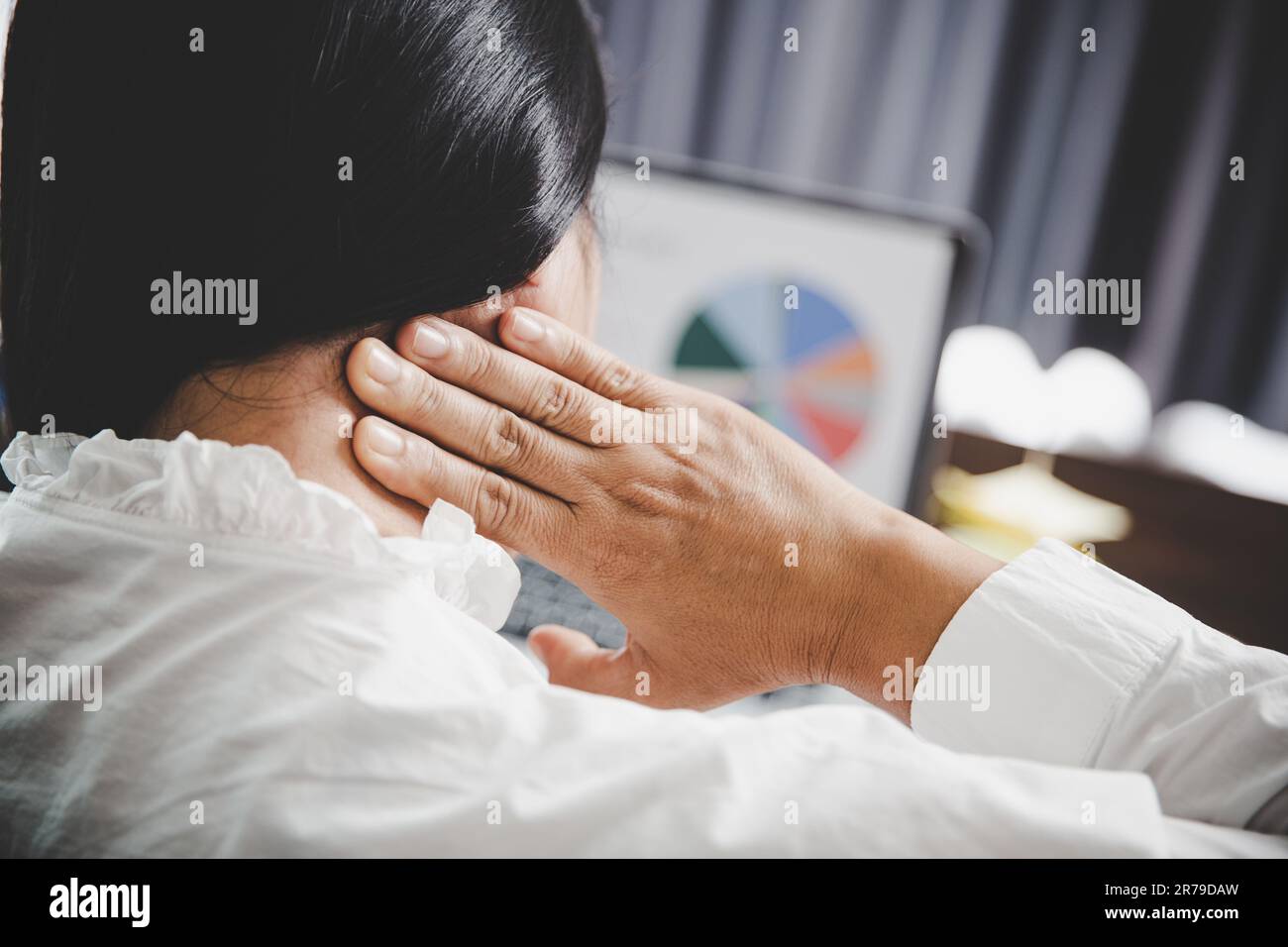 Young asian woman is sitting at work and has tension pain in her neck. Concept office syndrome backache pain from occupational disease, Female having Stock Photo