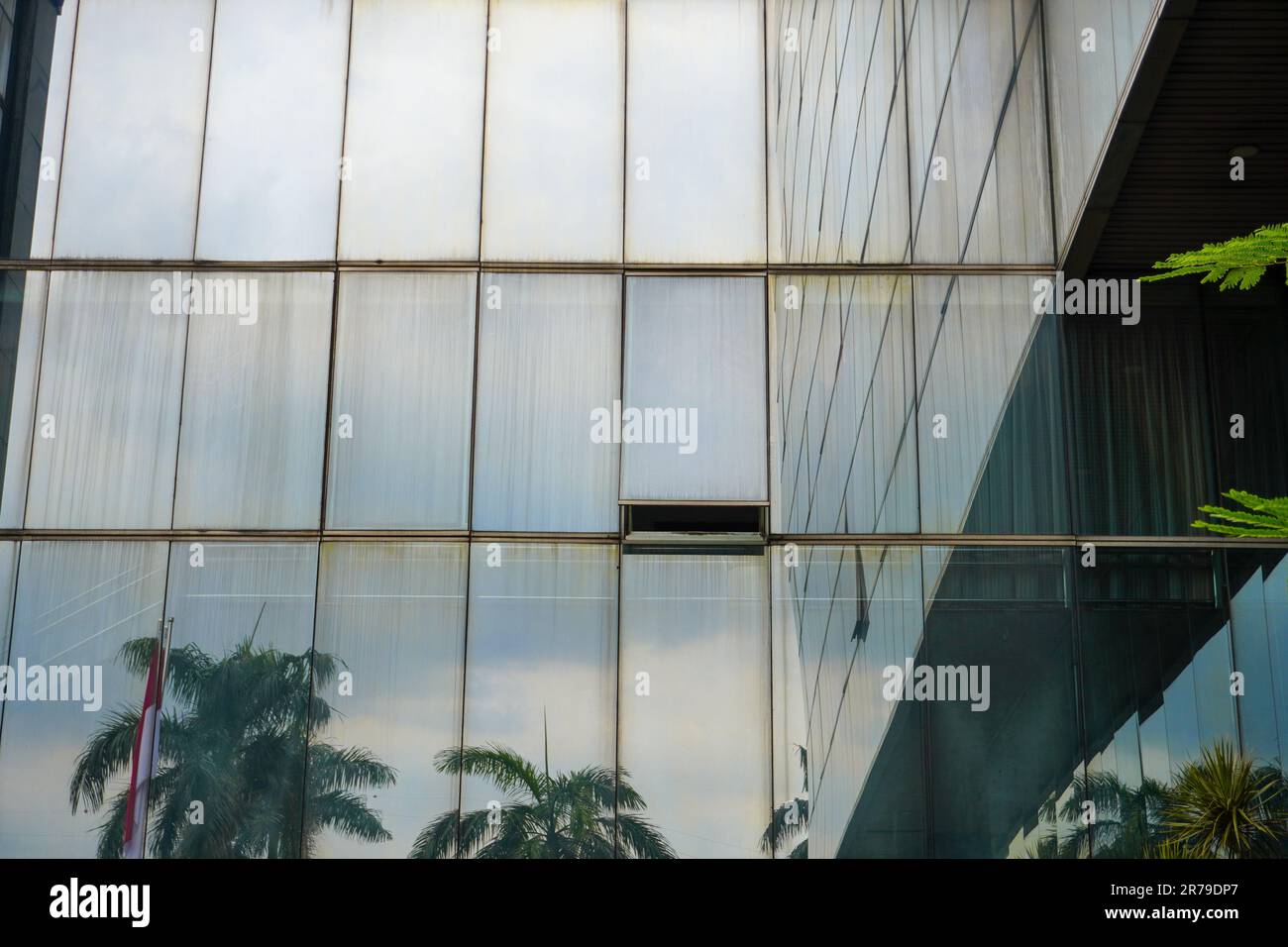 An older, filthy glass window opens in a multi-story skyscraper Stock Photo