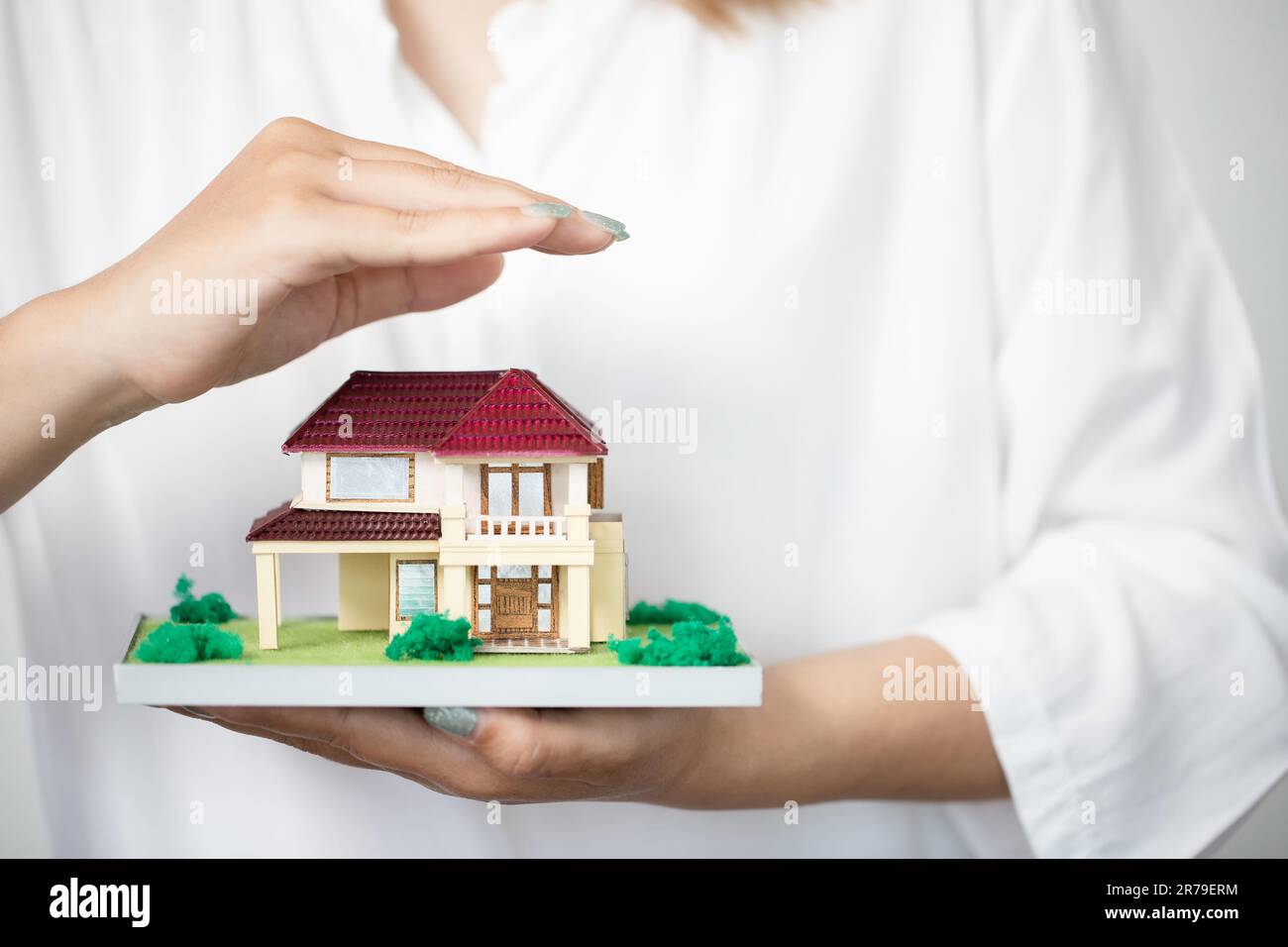 young woman use right hand to protect house model. real estate