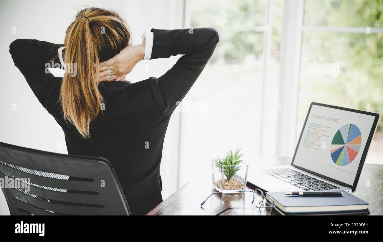 Young asian woman is sitting at work and has pain in her neck while she is sitting in the office working Stock Photo