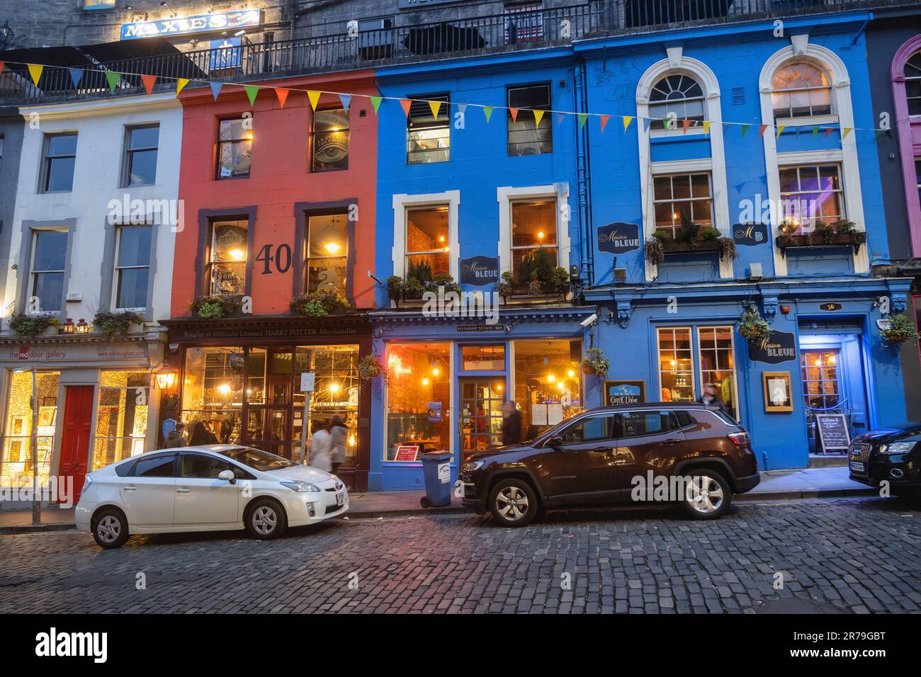 Evening at Victoria Street in city of Edinburgh with Maison Bleue restaurant and retail shop of Harry Potter officially licensed merchandise in Old To Stock Photo