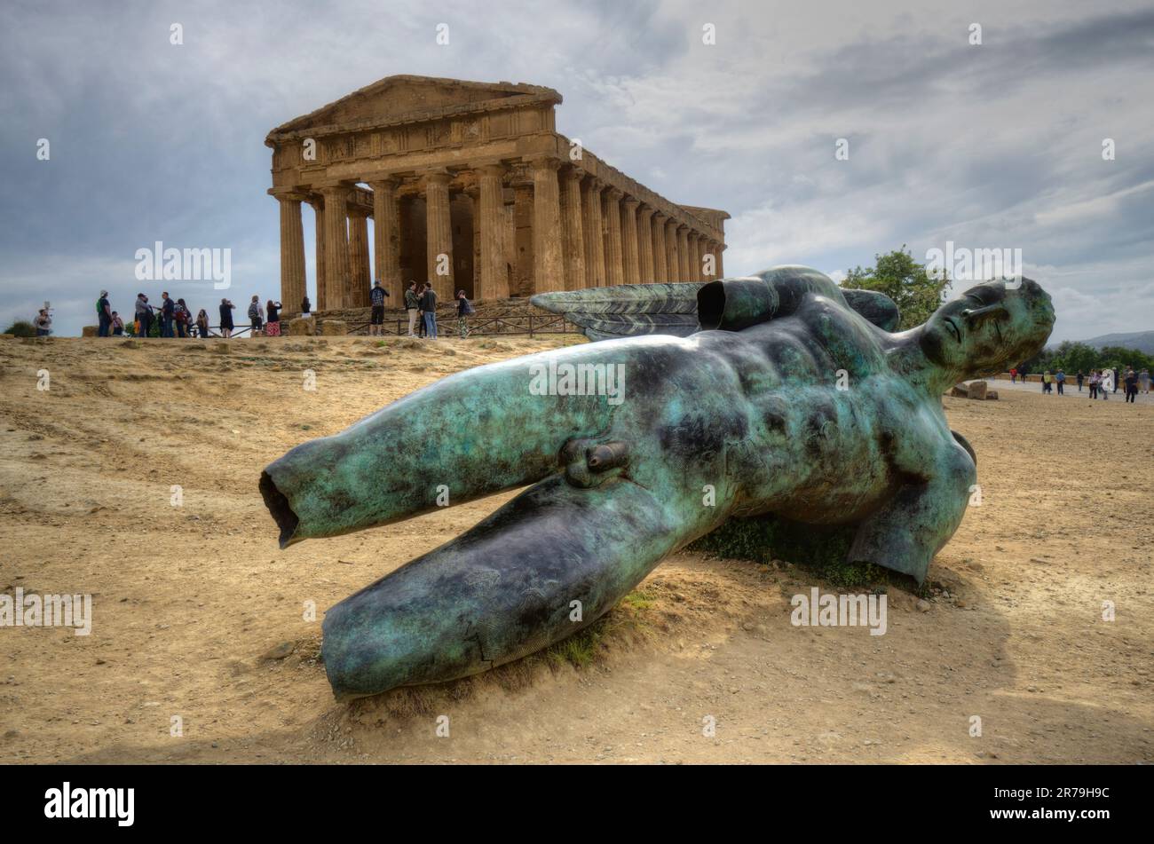 Temple of Concordia with fallen bronze green statue of Icarus in foreground and moody sky valley of temples agrigento sicily Stock Photo