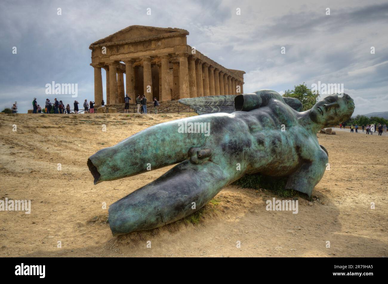 Temple of Concordia with fallen bronze green statue of Icarus in foreground and moody sky valley of temples agrigento sicily Stock Photo