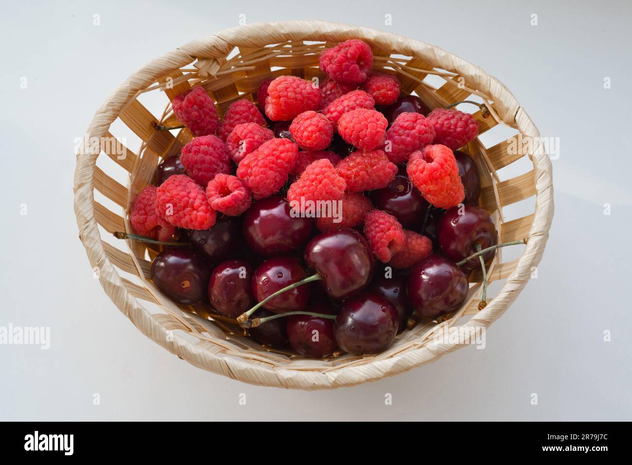 Cherry Vs Raspberry Size Fresh raspberries and cherries in a bucket on the white background ...