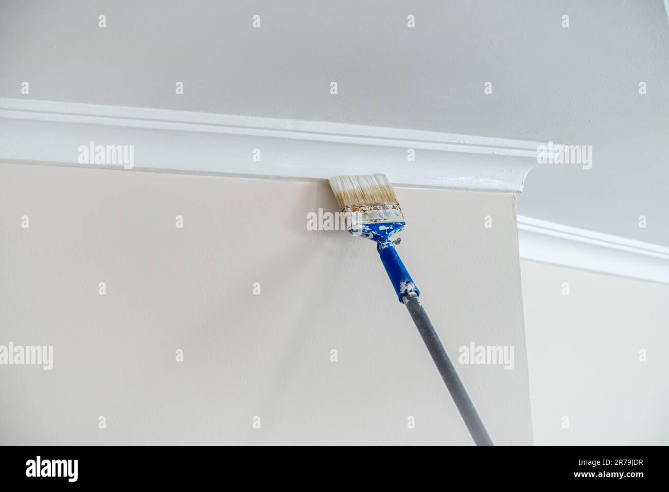 Painter painting the ceiling corners and led light edges with a brush before painting the room ceiling Stock Photo