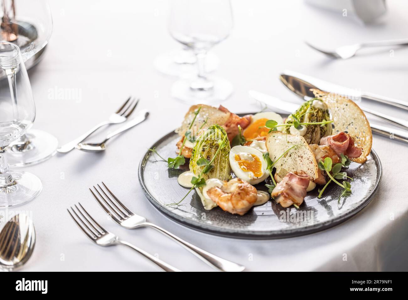 Luxury restaurant serves a modern twist on the classical ceasar salad on a dark plate. Stock Photo