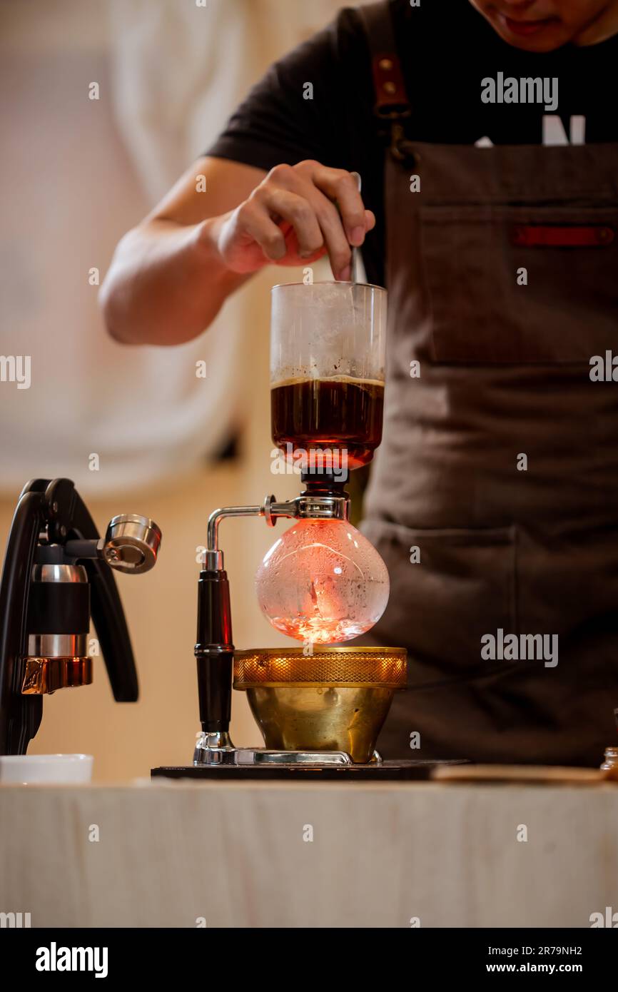 Professional coffee maker Barista using coffee siphon brewing hot